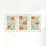 three orange and green flower prints on a white wall