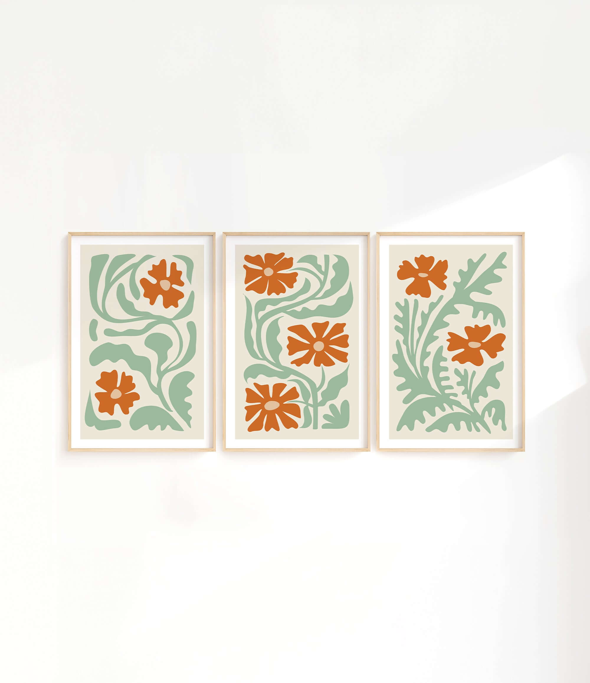 three orange and green flower prints on a white wall