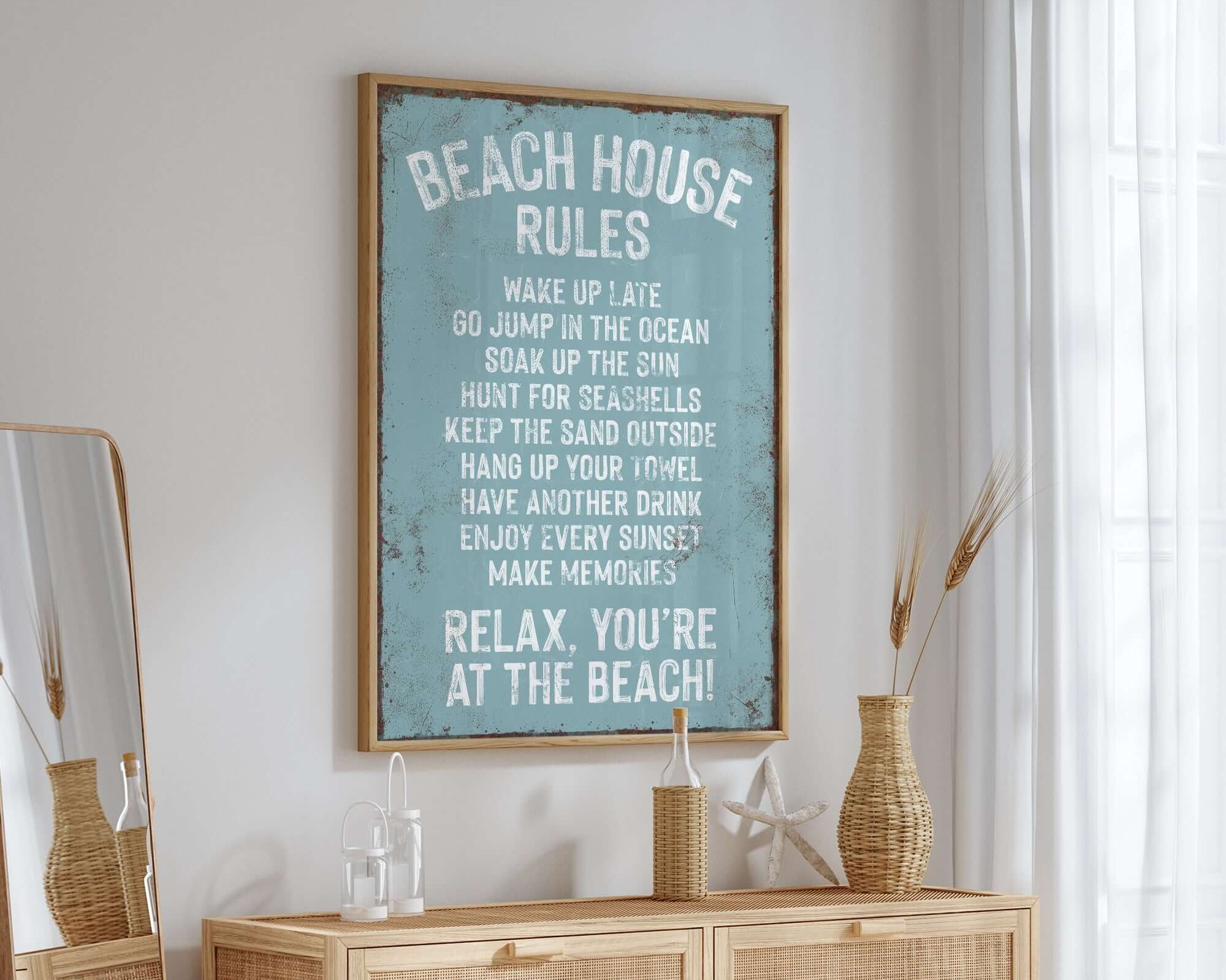 A Beach House Rules Sign with rusted edge in Tide color hangs above a wooden dresser in a bright, coastal-themed room, adding charming home wall decor to the relaxed space.