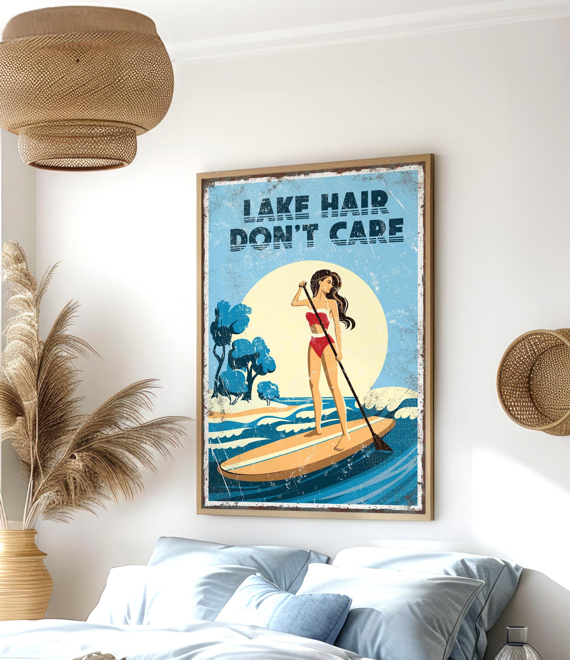 a framed poster of a woman paddleboarding on a lake, with the text "LAK E HAIR DON'T CARE" written on it.