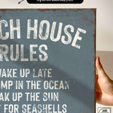 a hand holding a sign that says beach house rules