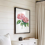 a white dresser with a framed picture of pink flowers hanging on the wall above it.