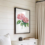 a white dresser with a framed picture of pink flowers hanging on the wall above it.