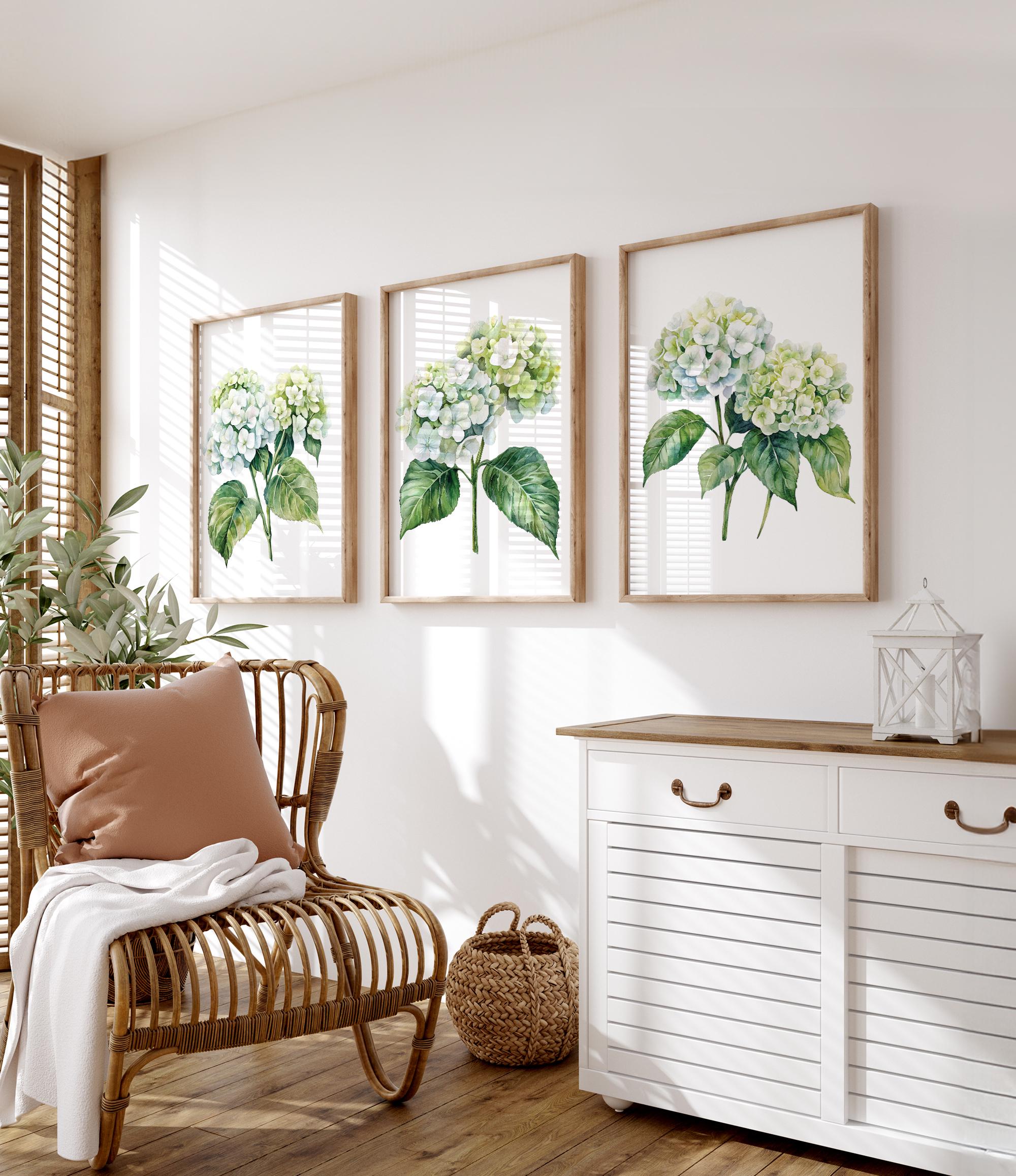 a cozy living room with a wicker chair, a white dresser, and three framed watercolor paintings of green hydrangeas on the wall.