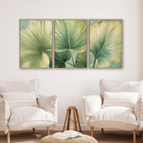 three large framed prints of green leaves hanging on a wall in a living room setting.