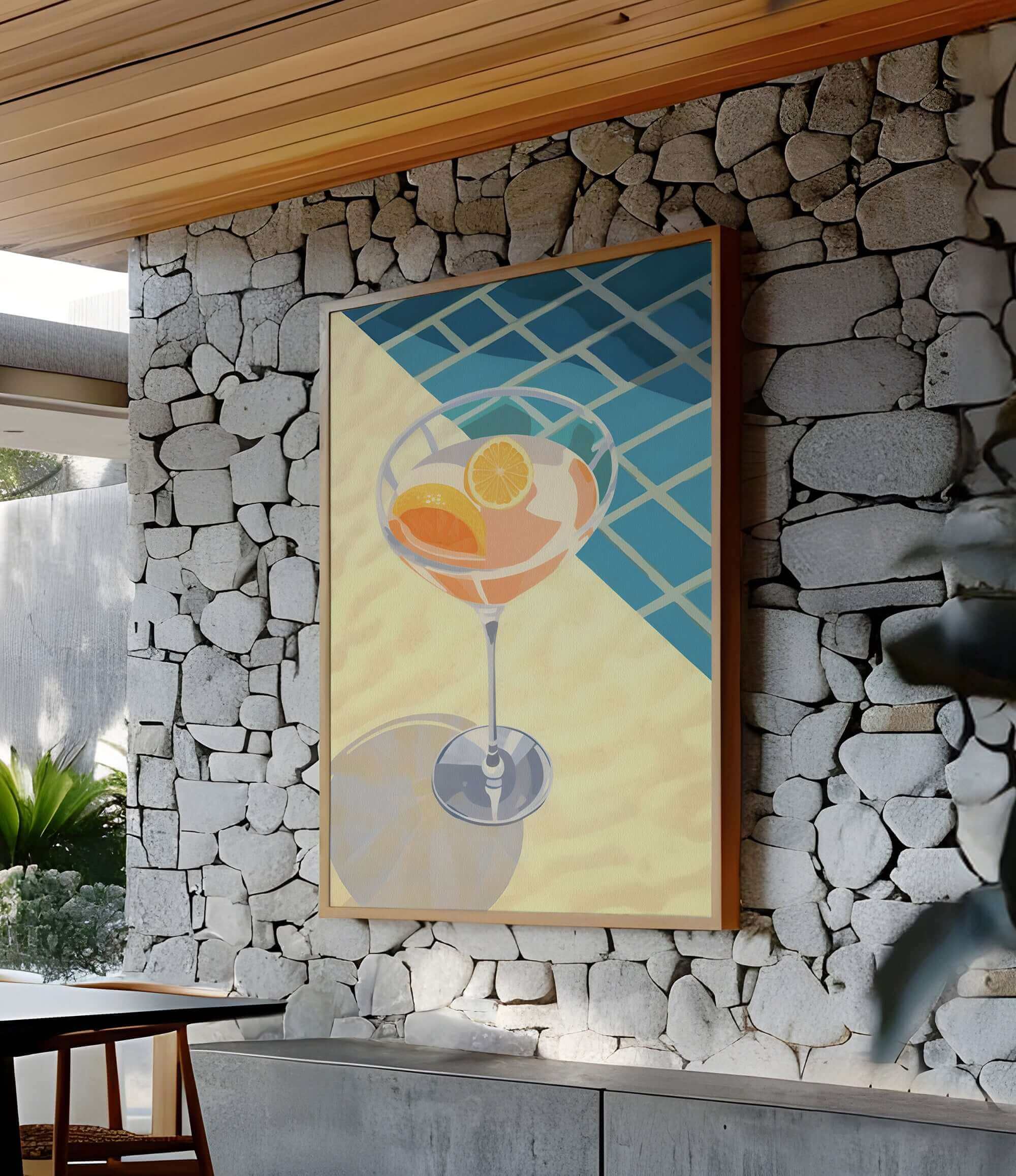 a large painting of a cocktail glass with orange slices, hanging on a stone wall.