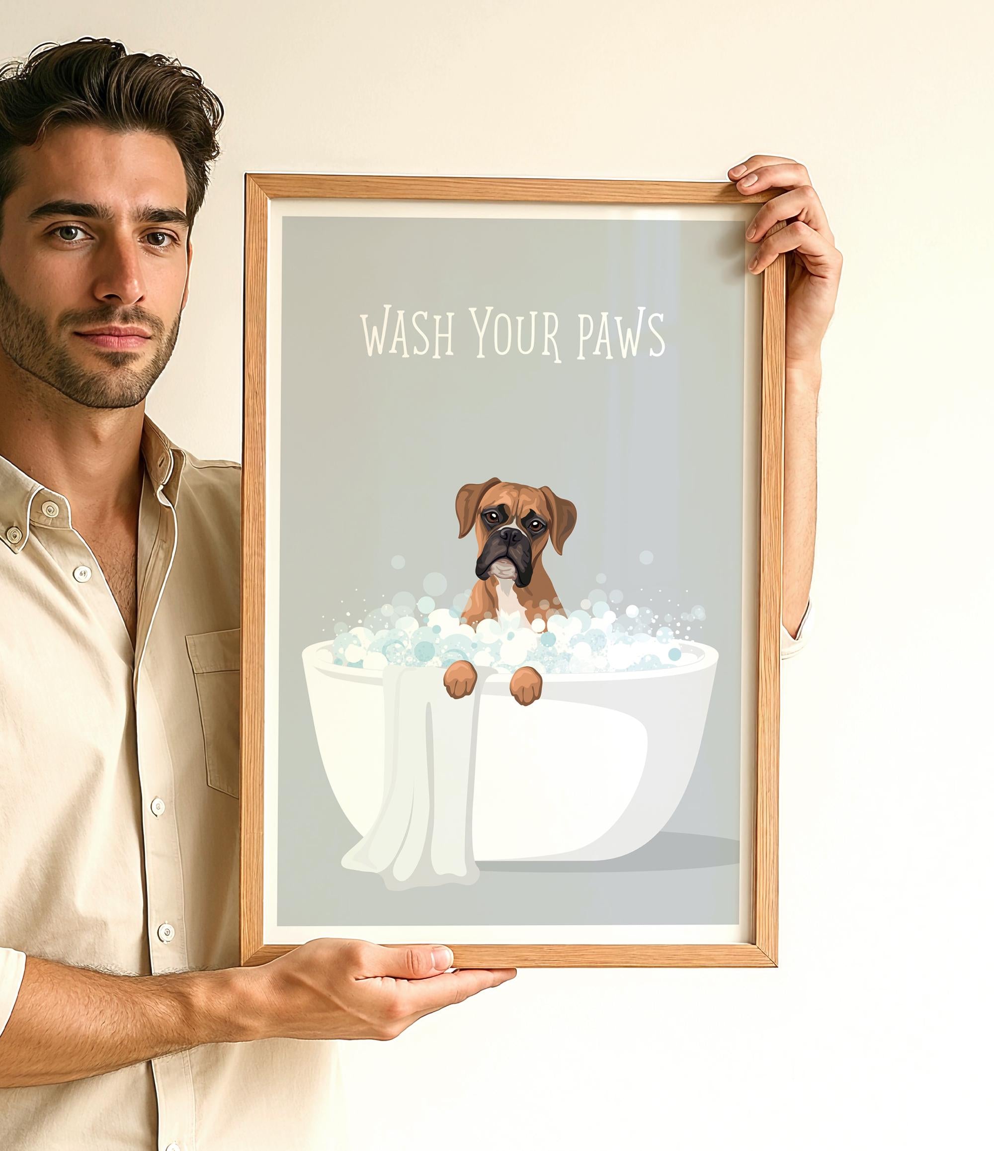 A man is holding up a framed poster with a dog sitting in a bathtub filled with bubbles, accompanied by the text "WASH YOUR PAWS".