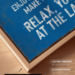 The image is a close-up of a blue canvas print with white text, placed on a wooden surface.