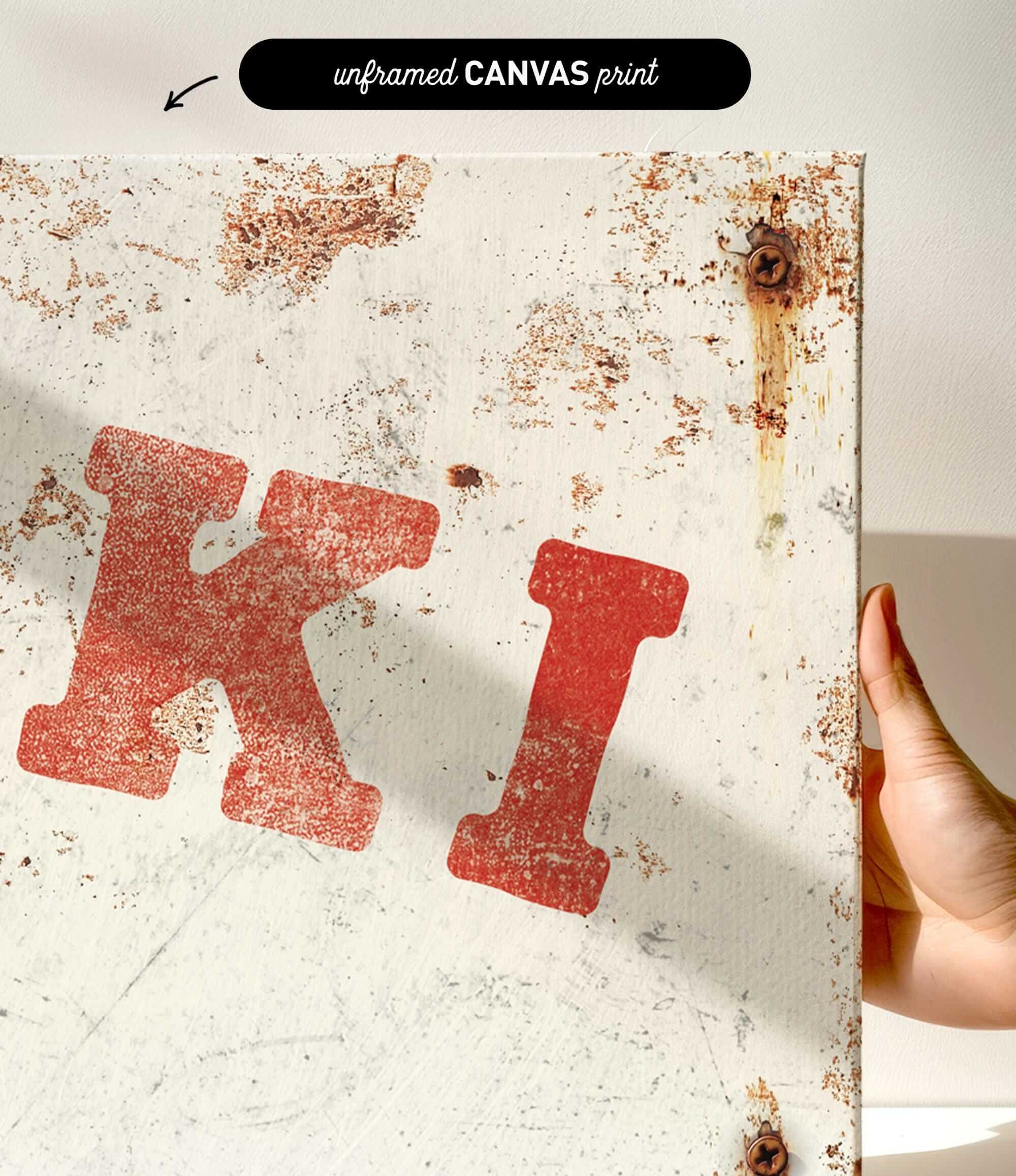 a close-up view of a white canvas print with a red letter "K" and some rust stains on it.