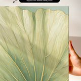 a close-up view of a leaf with intricate patterns and textures, held up against a white background.