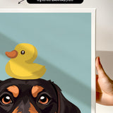 A hand is holding a framed print featuring a cartoon image of a dog with a yellow rubber duck on its head.
