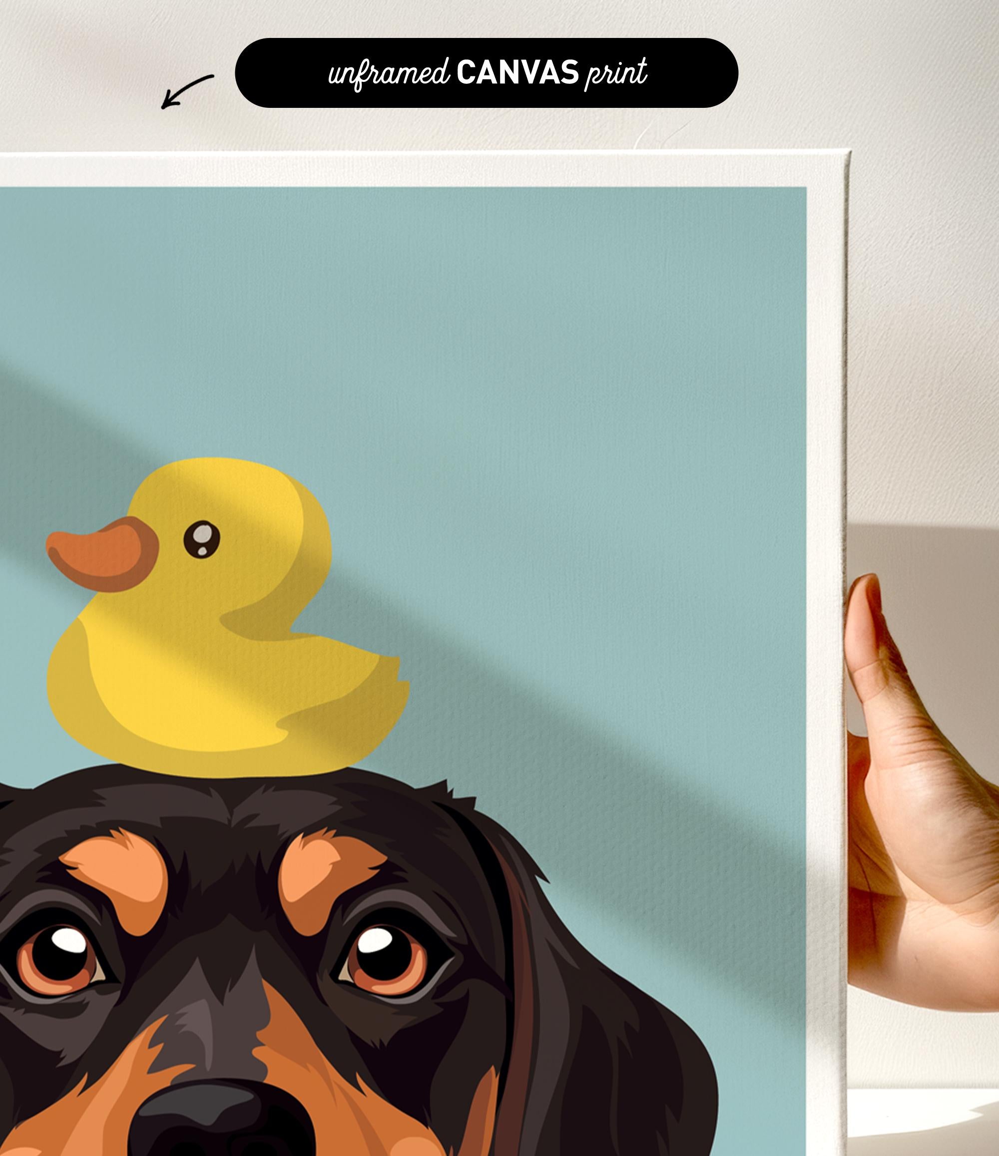 A hand is holding a framed print featuring a cartoon image of a dog with a yellow rubber duck on its head.