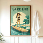 a framed poster of a woman paddleboarding on a lake, with the text "LAKELIFE" prominently displayed.