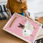 A woman is holding a framed poster with a dog in a bathtub, which has a pink background and the text "Please Don't Bathe Your Dogs" written on it.