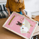 A woman is holding a framed poster with a dog in a bathtub, which has a pink background and the text "Please Don't Bathe Your Dogs" written on it.