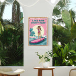 a poster with a woman paddleboarding on a lake, surrounded by tropical plants, with the text "LAKESHAIR DON'T CARE" displayed prominently.
