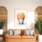 a cozy living room with a brown leather sofa adorned with striped pillows. Above the sofa, a framed watercolor painting of a colorful cupcake with a flower on top is displayed on the wall. The room is decorated with potted plants and wooden shutters, creating a warm and inviting atmosphere.