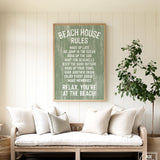 Cozy couch with white pillows in a beach house, topped by the Beach House Rules Sign in painted wood with seagrass, adding the perfect coastal wall art above.