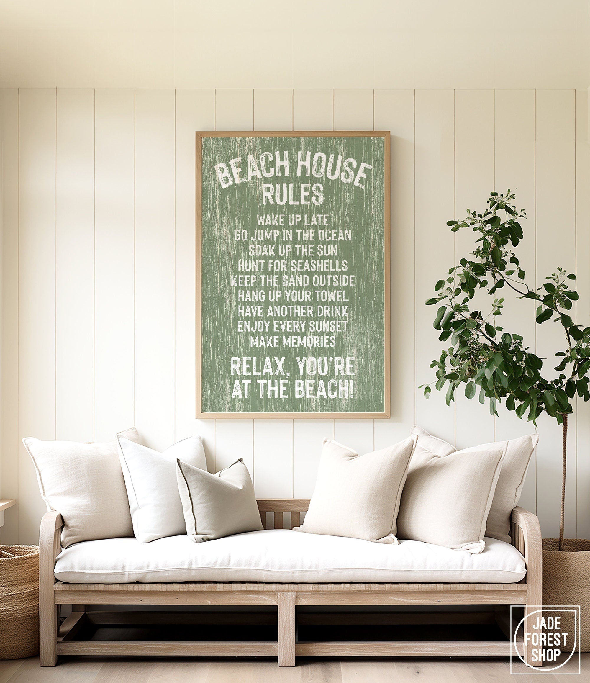 Cozy couch with white pillows in a beach house, topped by the Beach House Rules Sign in painted wood with seagrass, adding the perfect coastal wall art above.