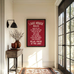 a hallway with a framed sign that reads "LAKESHORE RULES" hanging on the wall. The hallway has a wooden table with a vase of flowers, a rug, and a window with a view of trees outside.