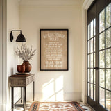 a beach house with a framed sign that reads "BEACH HOUSE RULES" hanging on the wall. The room has a wooden table, a vase with flowers, and a rug on the floor. There is also a large window that allows natural light to enter the space.