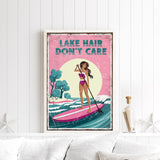 a framed poster with a woman paddleboarding on a lake, with the text "LAKESHAIR DON'T CARE" written on it.
