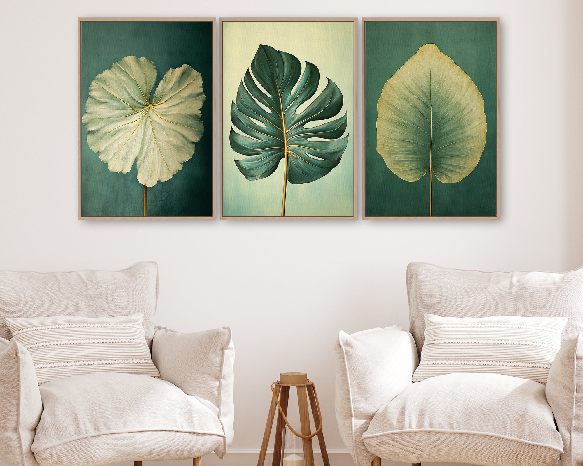 a living room with three framed paintings of leaves hanging on the wall above two white armchairs.