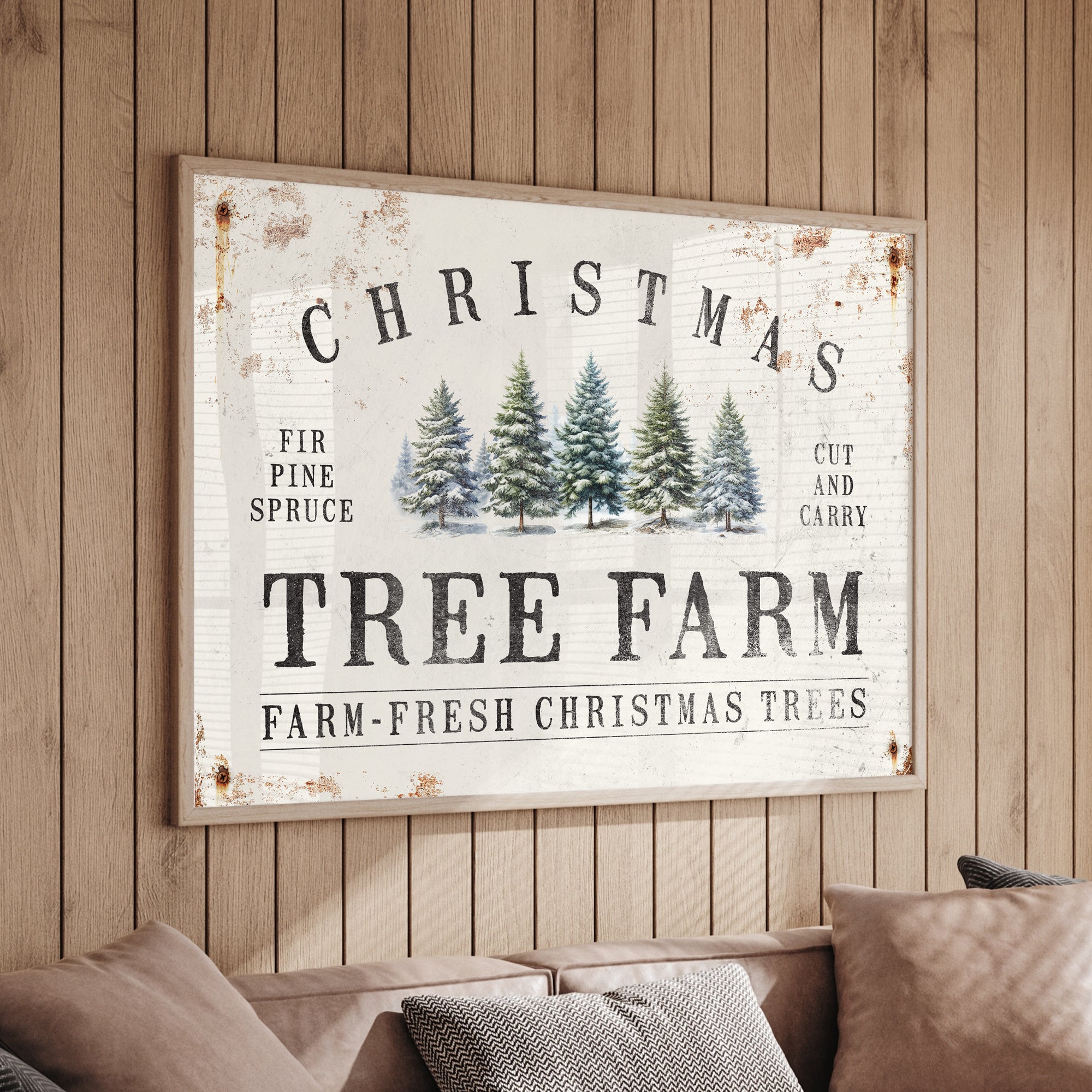 A framed "Christmas Tree Farm" sign with illustrated trees hangs on a wooden wall above a beige couch.