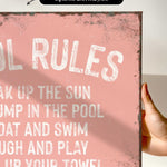 a hand holding a pink sign that says pool rules