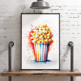A framed watercolor painting of a bucket of popcorn is displayed on a wooden shelf against a white brick wall.