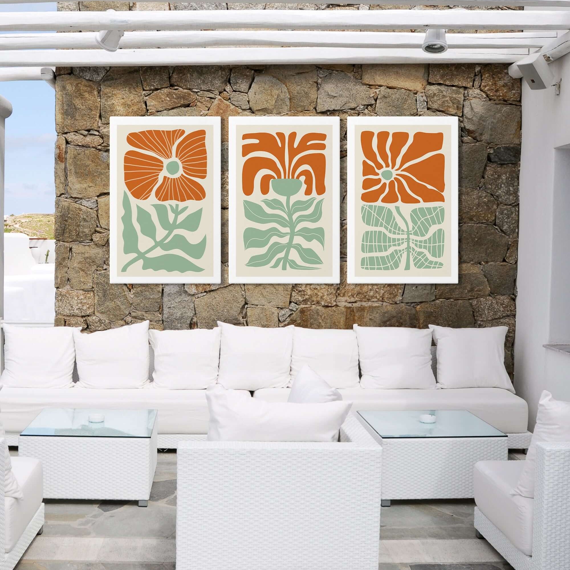 White outdoor lounge with wicker sofas, glass tables, and the Flower Blocks Triptych | Set of Three Prints | 012—vibrant orange and green floral art on the stone wall—perfect for stylish home decor.