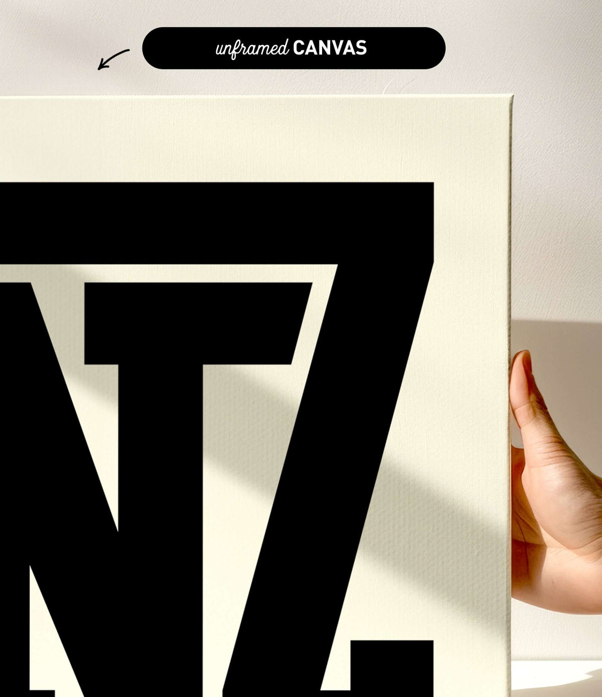 Close-up of a hand holding an unframed Yinz Sign Print, Off White—modern farmhouse home decor featuring bold black letters "Yinz" on an off-white background, perfect for any space.