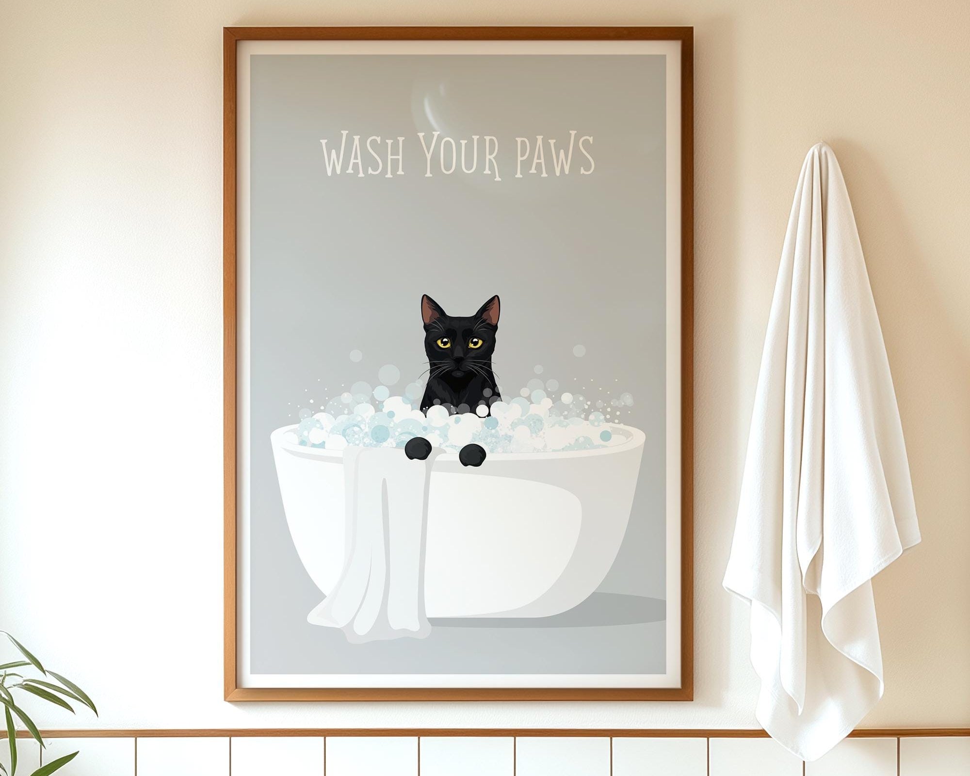 A framed poster with a black cat sitting in a white bathtub filled with bubbles, accompanied by the text "WASH YOUR PAWS" on the poster.