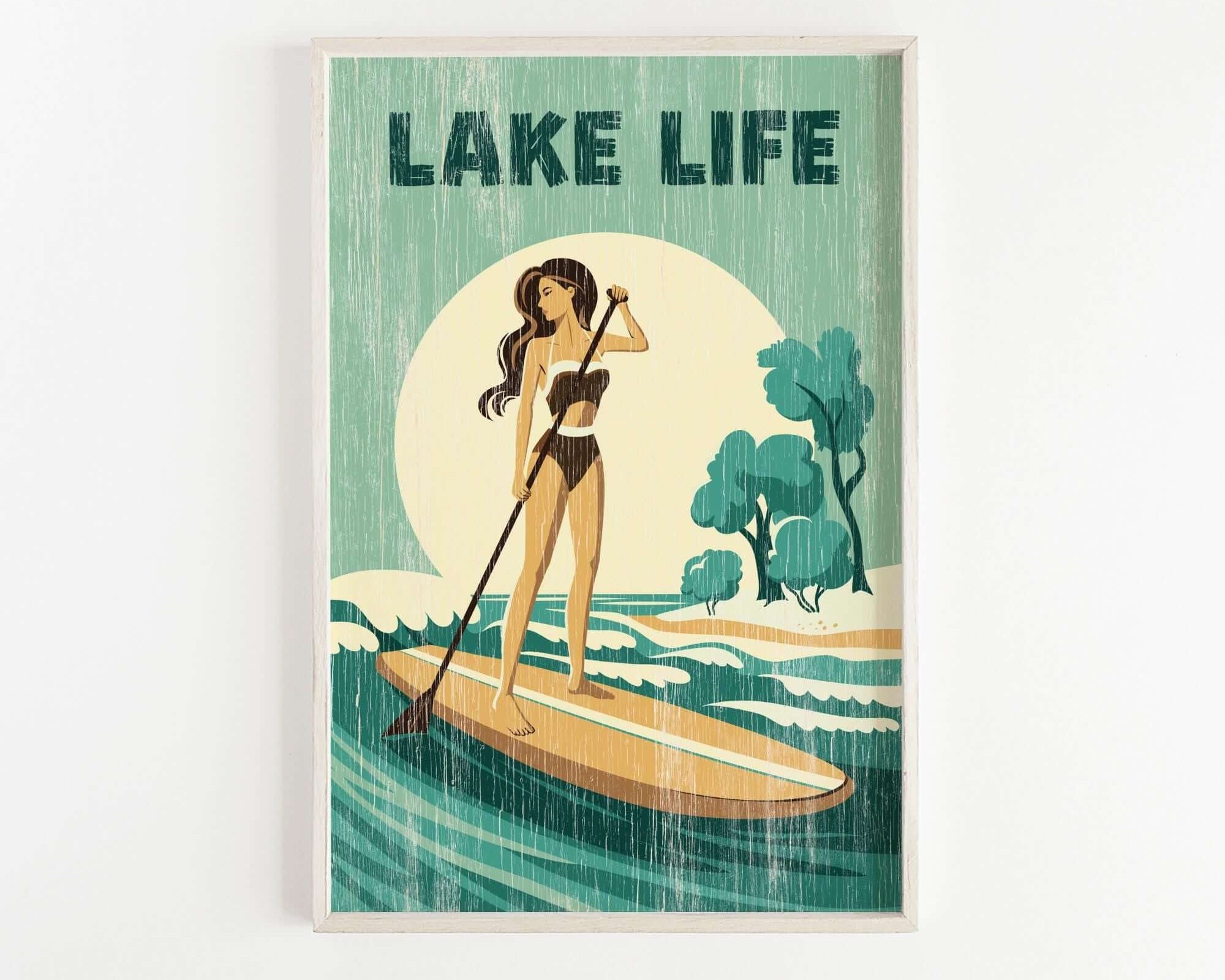 A woman in a bathing suit stands on a paddleboard, holding a paddle and facing a large body of water with trees in the background.