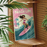 A framed poster featuring a woman surfing on a pink surfboard, with palm trees and waves in the background, is displayed on a wooden shelf.
