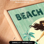 The image is a framed artwork featuring a beach scene with palm trees and a woman. The artwork is framed in a natural frame and has artwork wrapped around the sides.