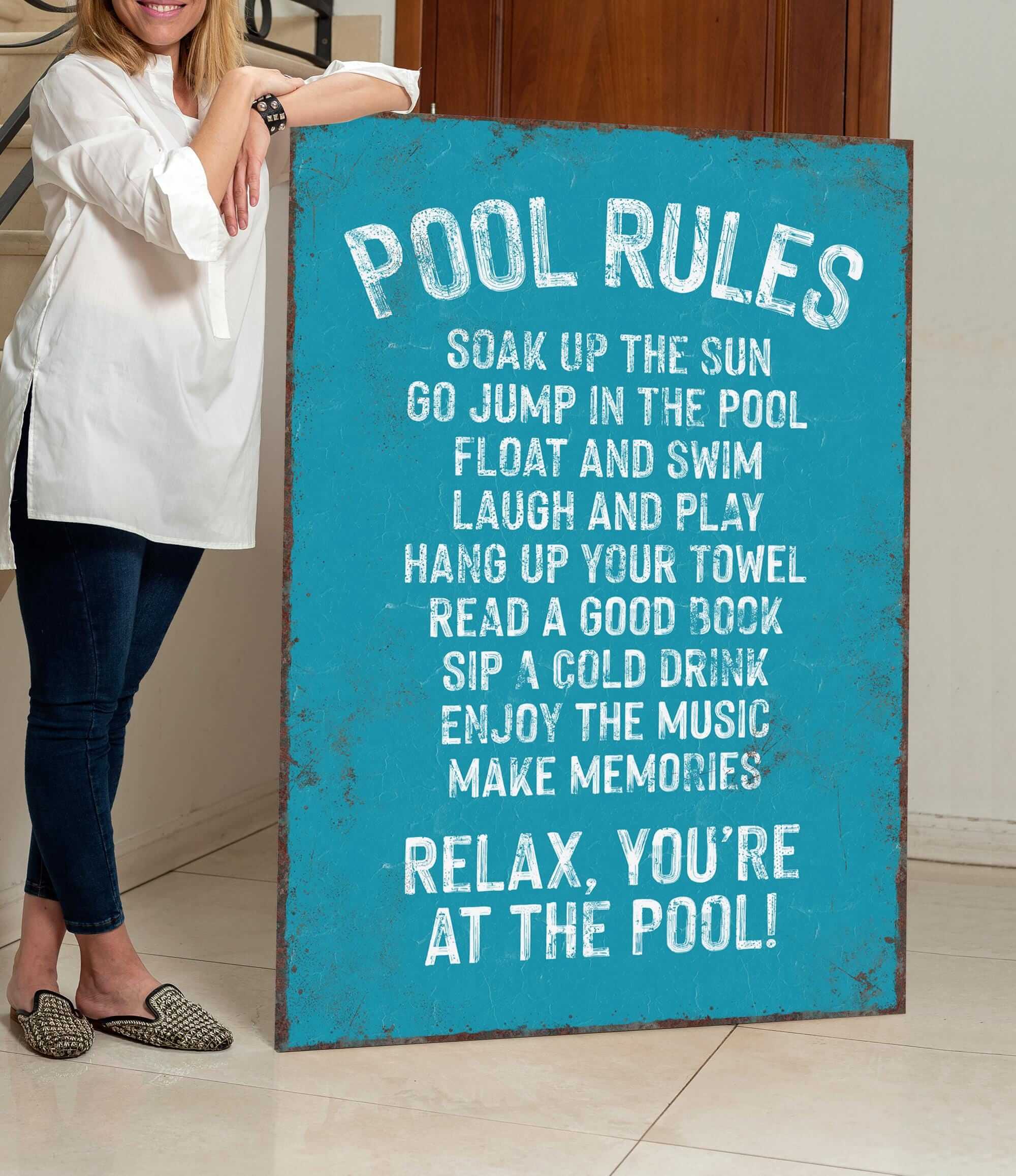 a woman standing next to a pool rules sign