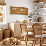 A cozy kitchen scene with a dog resting on the floor, a wooden table and chairs, and a rustic wall sign that reads "Autumn Leaves and apples please".