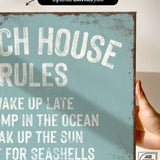 a hand holding a sign that says beach house rules