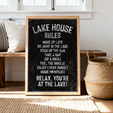 A chalkboard sign with the text "LAKESHOUSE RULES" written on it, placed on a wooden floor next to a woven basket.