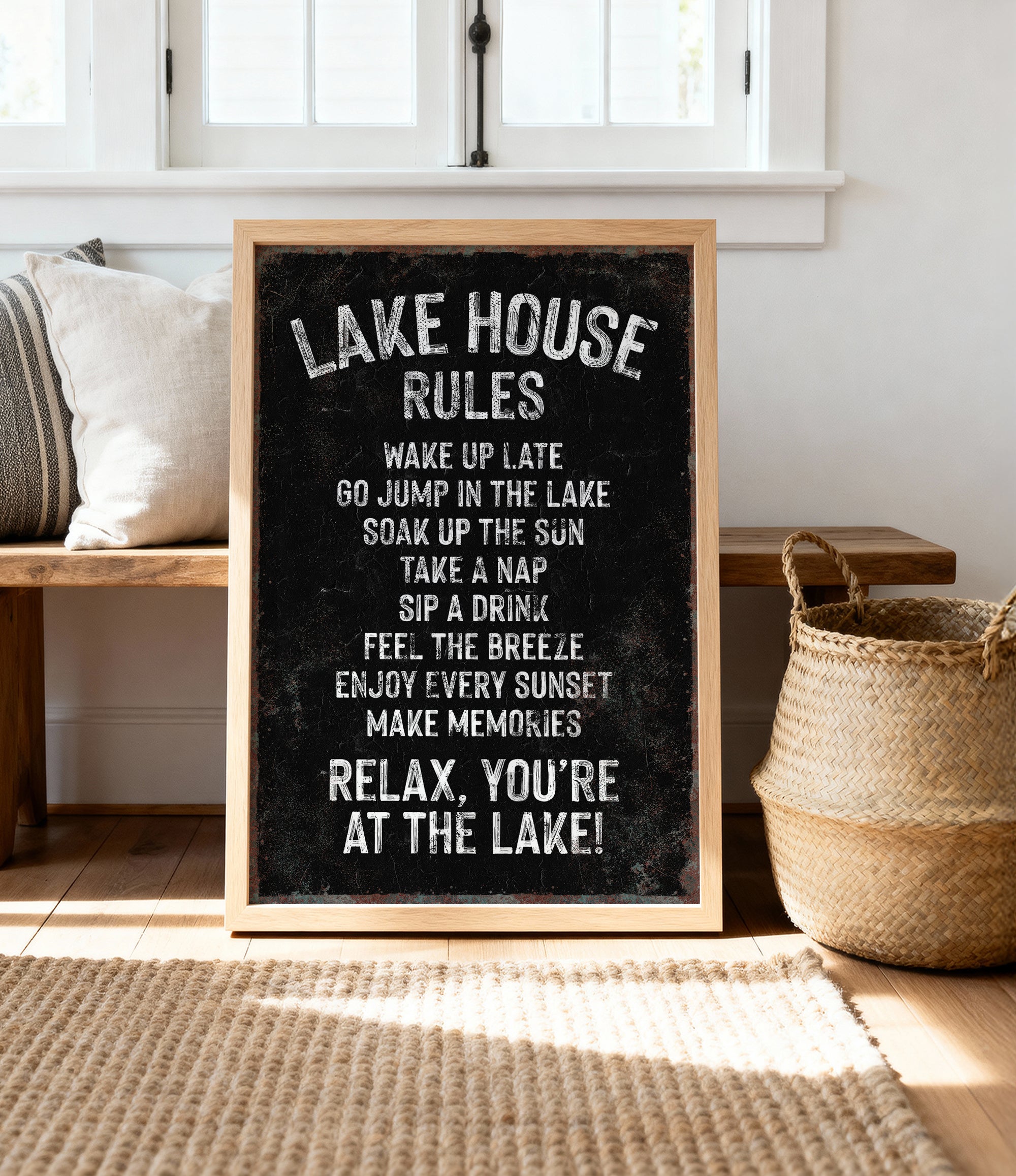 A chalkboard sign with the text "LAKESHOUSE RULES" written on it, placed on a wooden floor next to a woven basket.