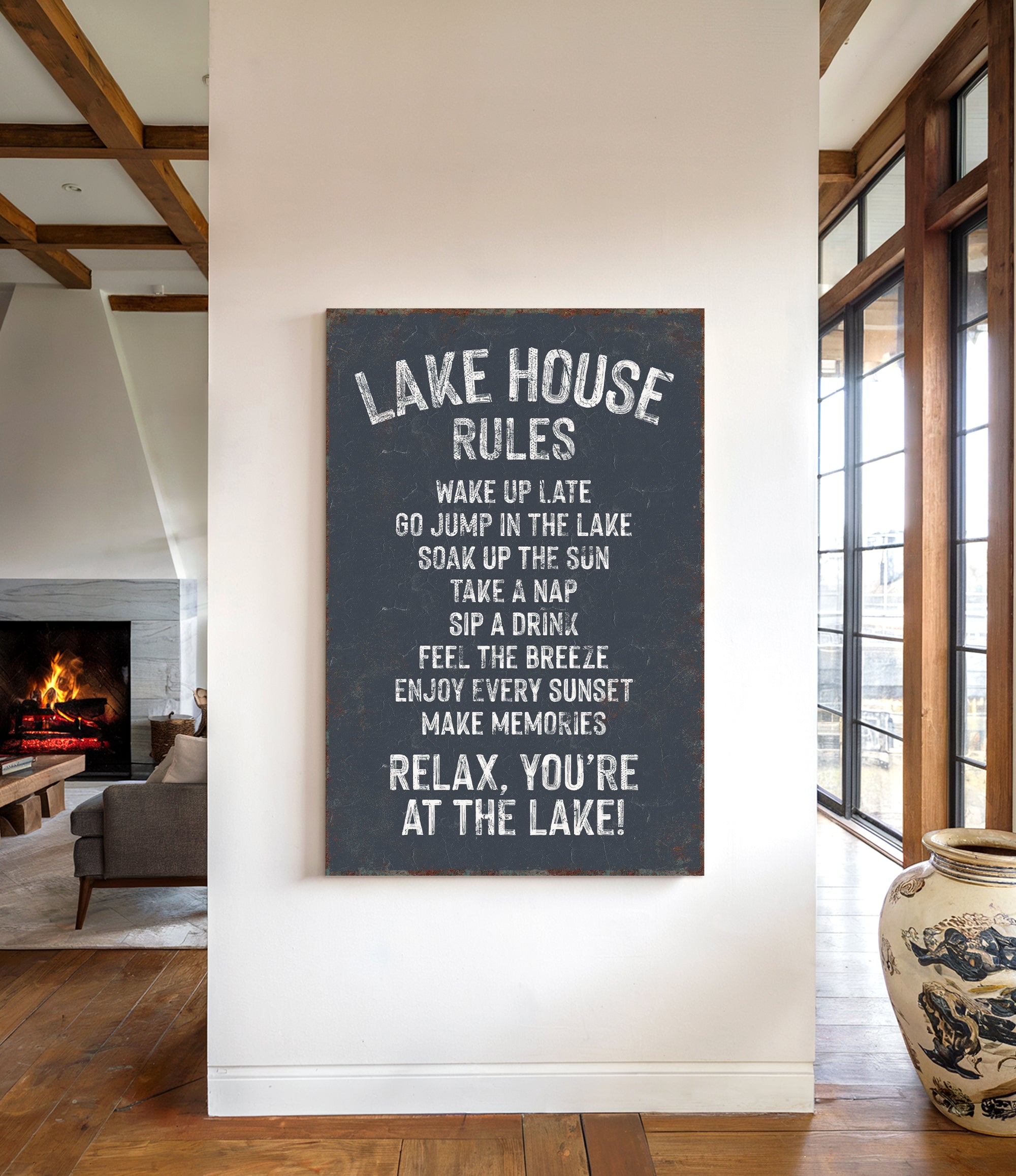 a sign that reads "Lake House Rules" hanging on a wall in a room with a fireplace and a vase.
