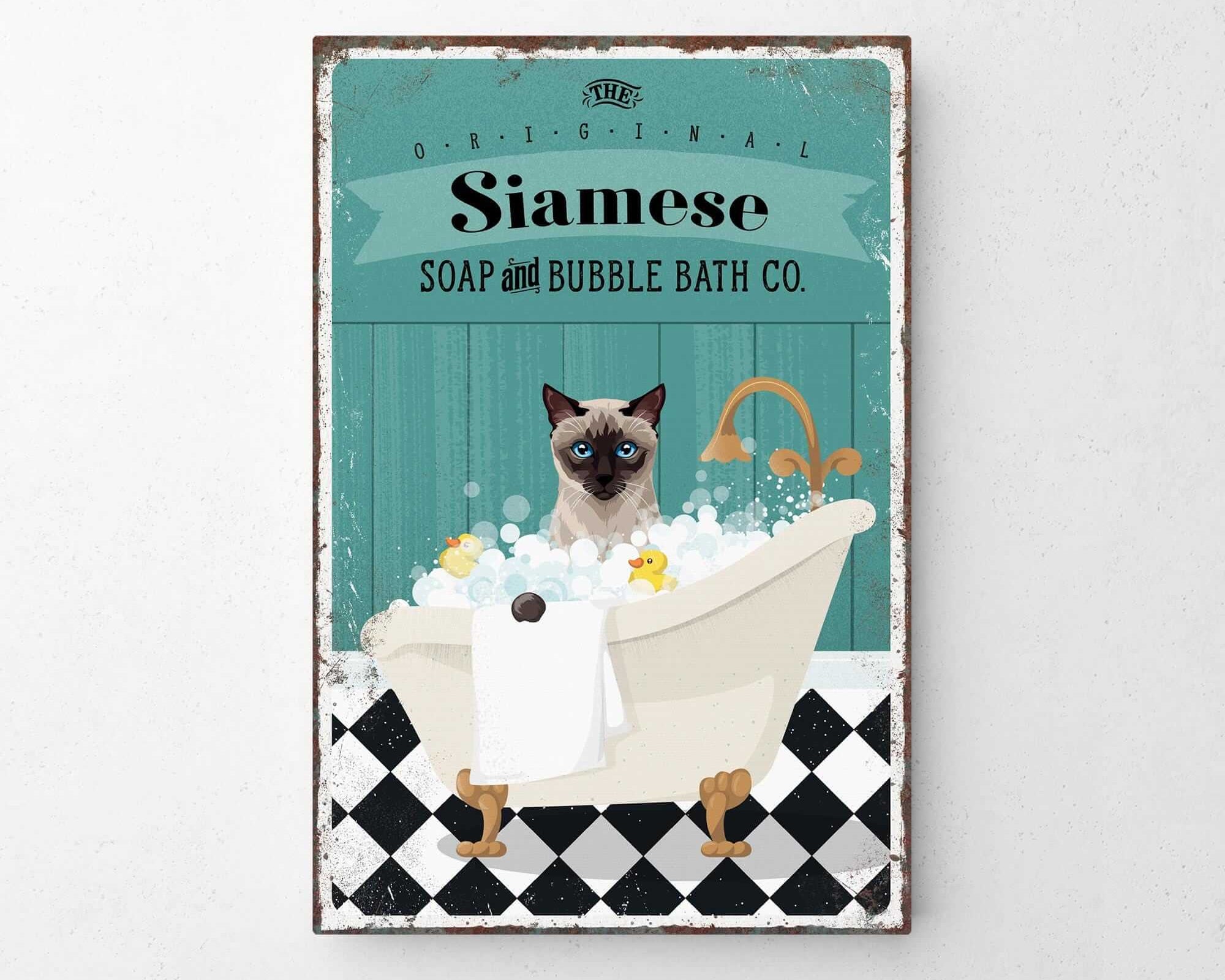 A vintage-style poster advertising Siamese Soap and Bubble Bath Co., featuring a Siamese cat sitting in a bathtub filled with bubbles.