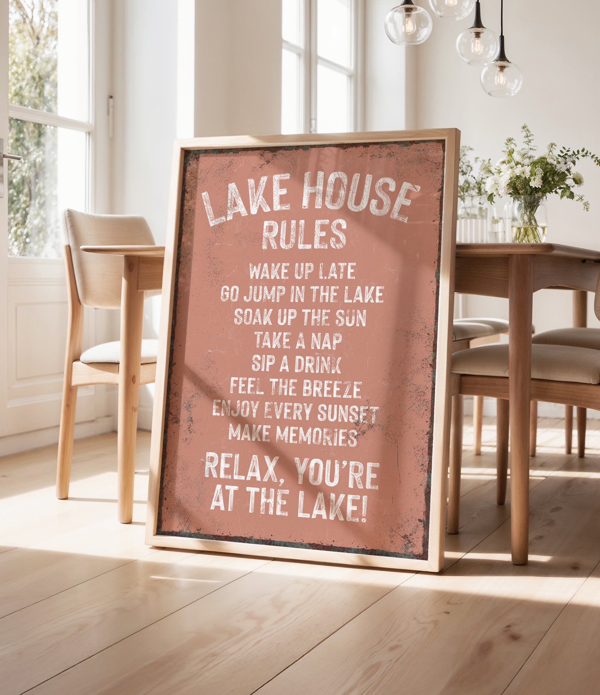 a sign that reads "LAKESHOUSE RULES" in a rustic wooden frame, placed in a room with a dining table and chairs.