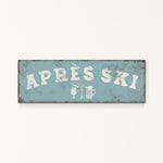 A weathered sign with the text "APRÈS SKI" in white letters, along with icons representing a beer and a martini glass.