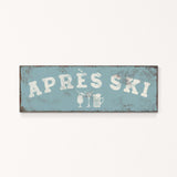 A weathered sign with the text "APRÈS SKI" in white letters, along with icons representing a beer and a martini glass.