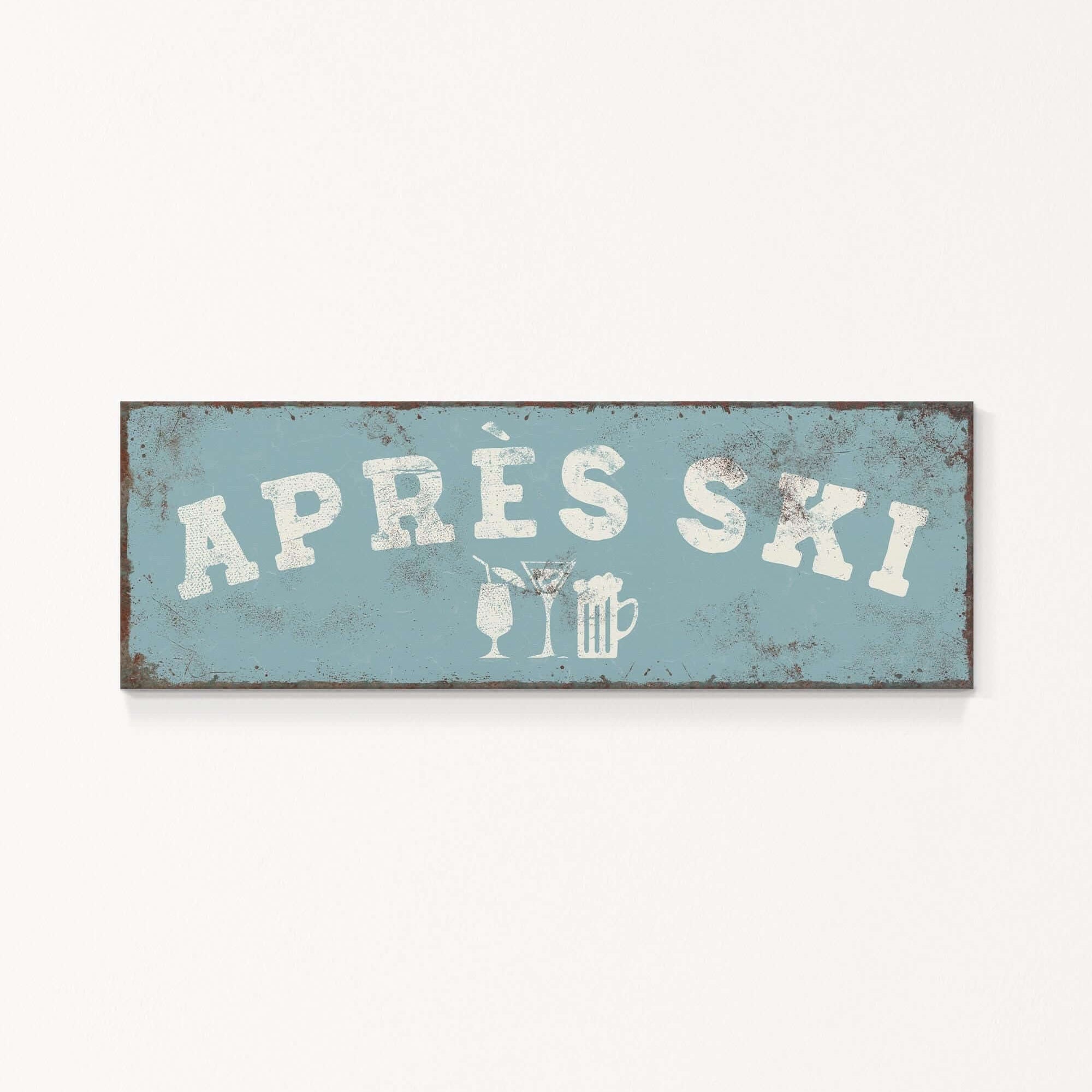 A weathered sign with the text "APRÈS SKI" in white letters, along with icons representing a beer and a martini glass.