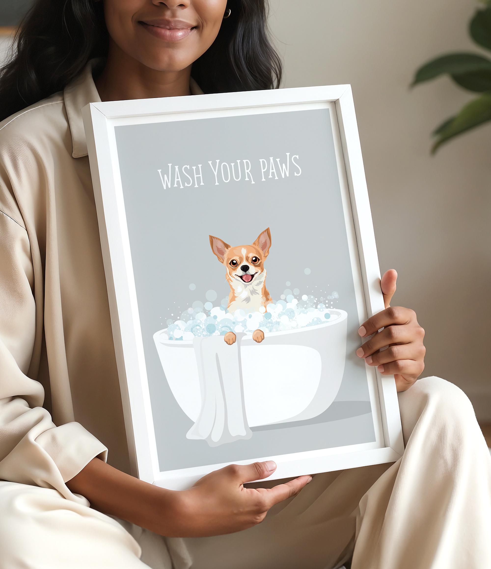 A woman is holding a framed poster with an illustration of a dog sitting in a bathtub filled with bubbles, accompanied by the text "WASH YOUR PAWS".