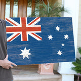 a man holding a wooden sign with the flag of australia on it