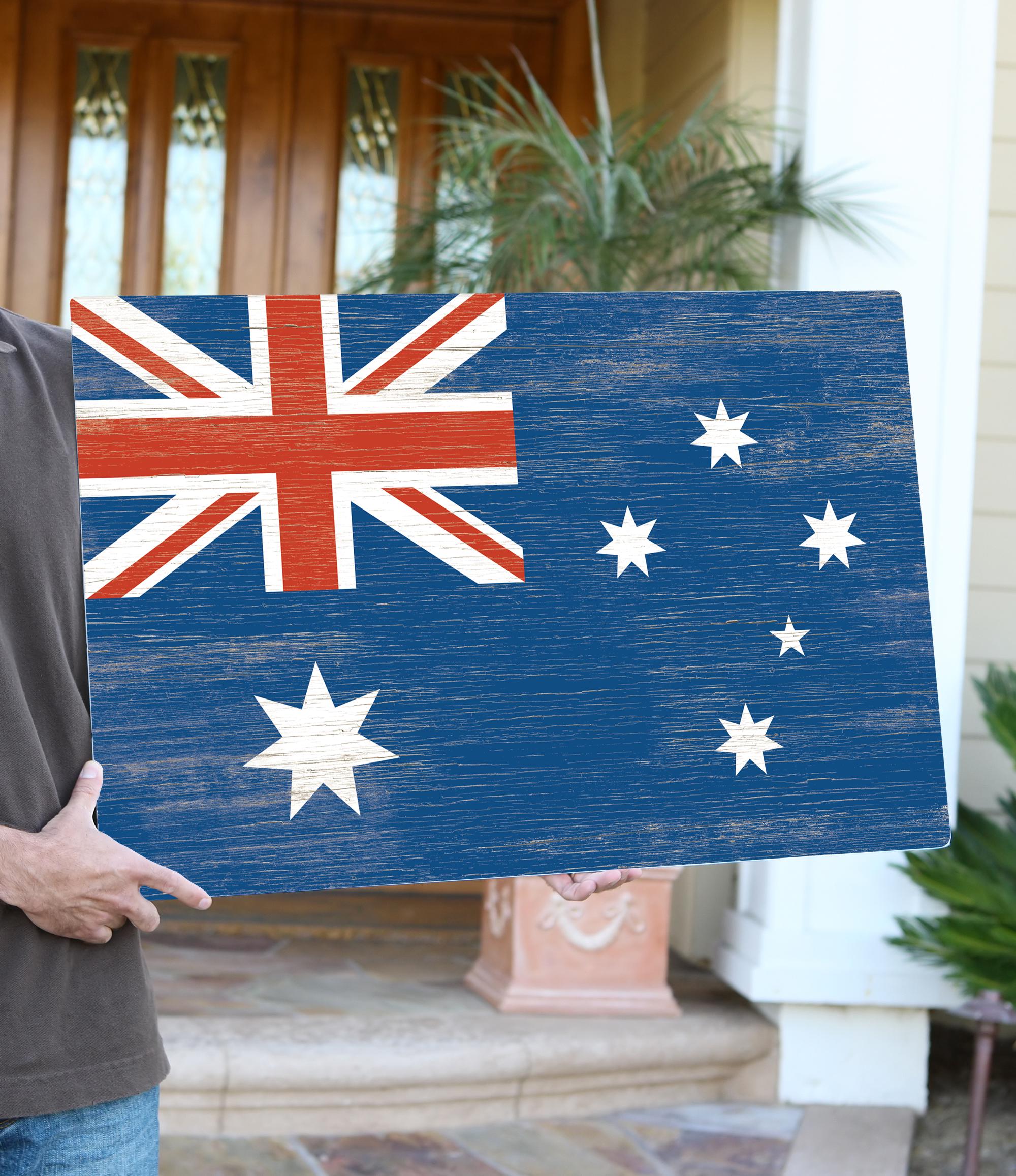 a man holding a wooden sign with the flag of australia on it